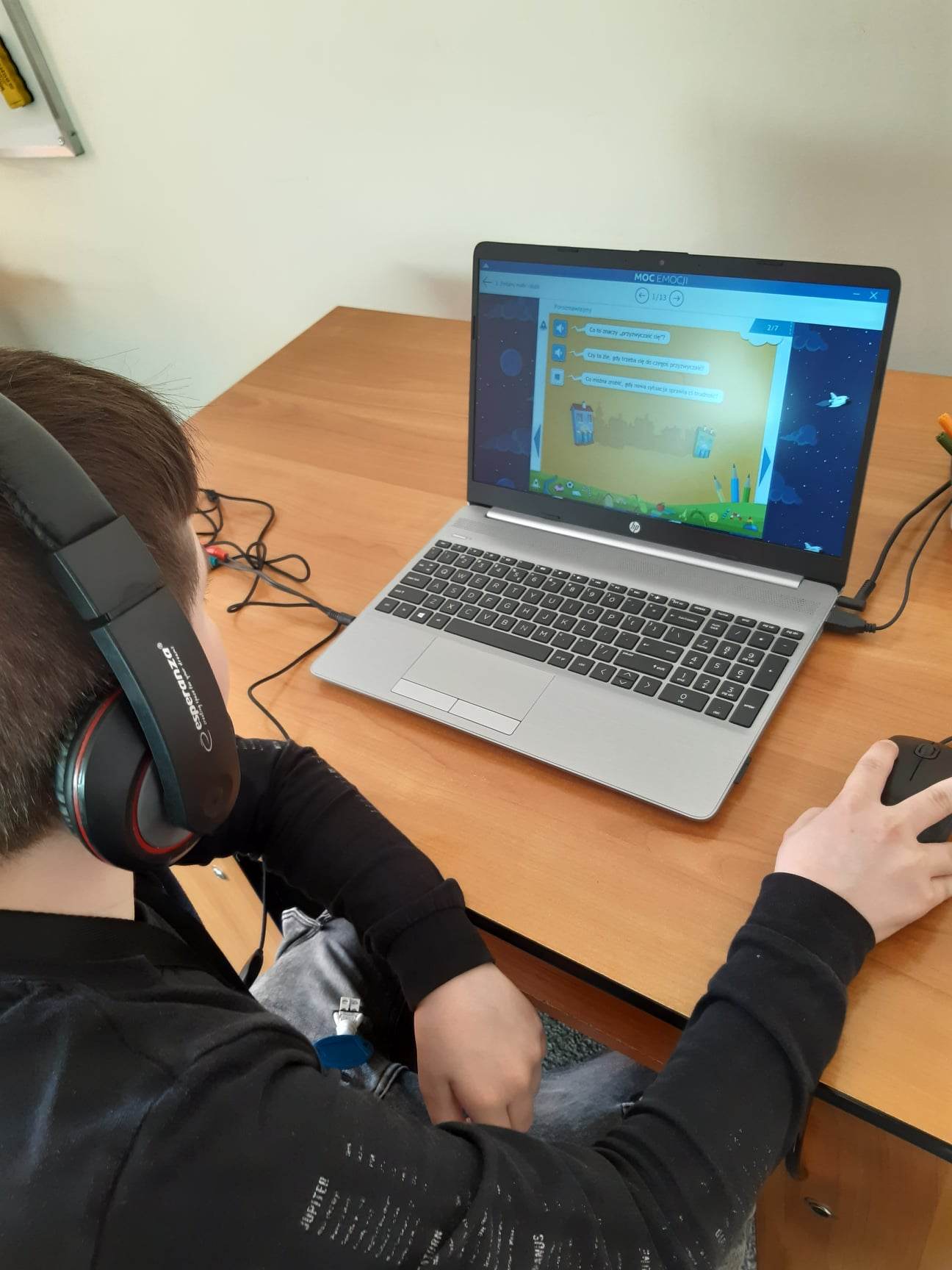 Na zdjęciu chłopiec w słuchawkach korzysta z aplikacji komputerowejjpg