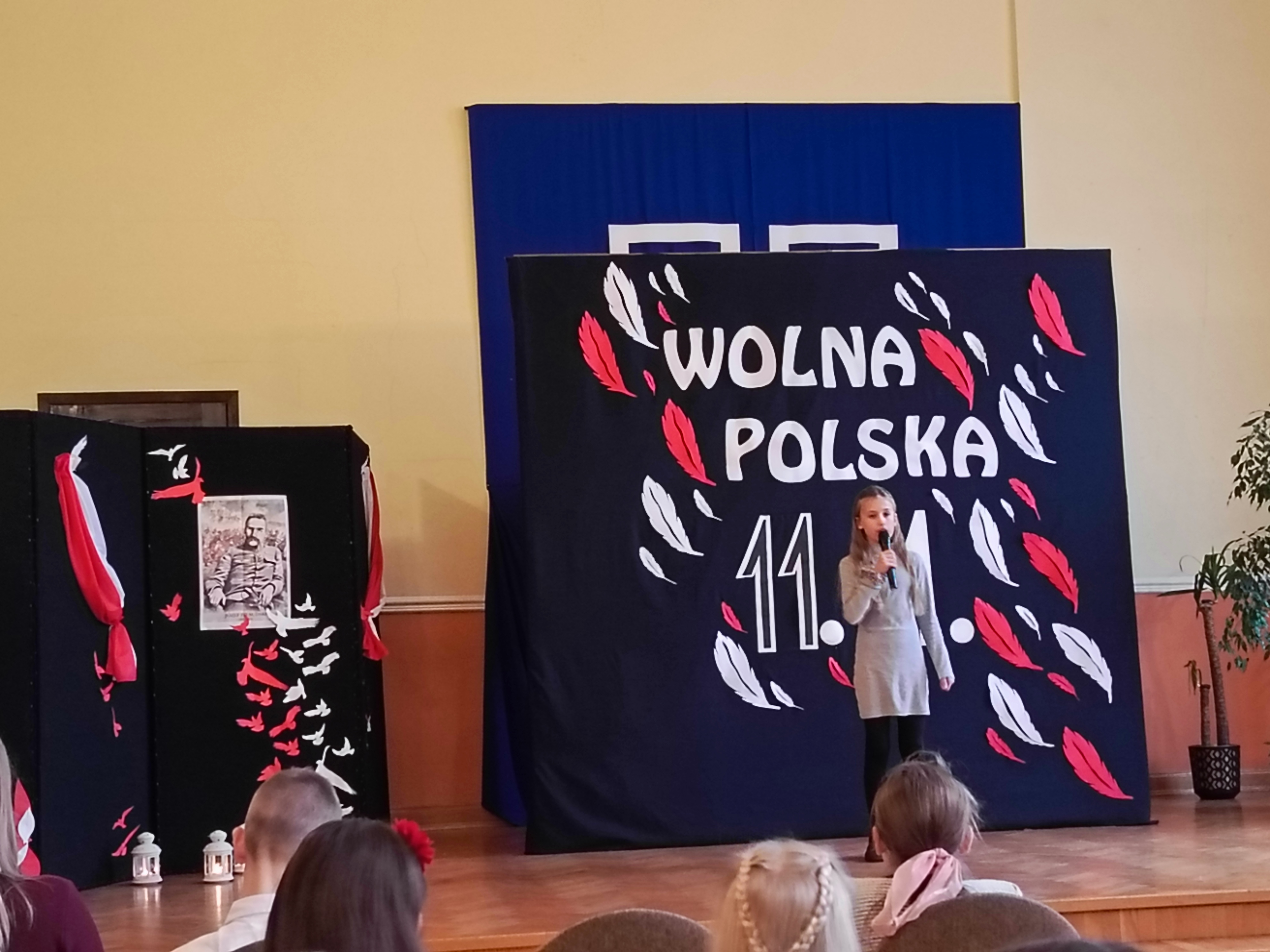 Na scenie dziewczynka z mikrofonem, w tle tablica z napisaem: 11.11 Wolna Polska